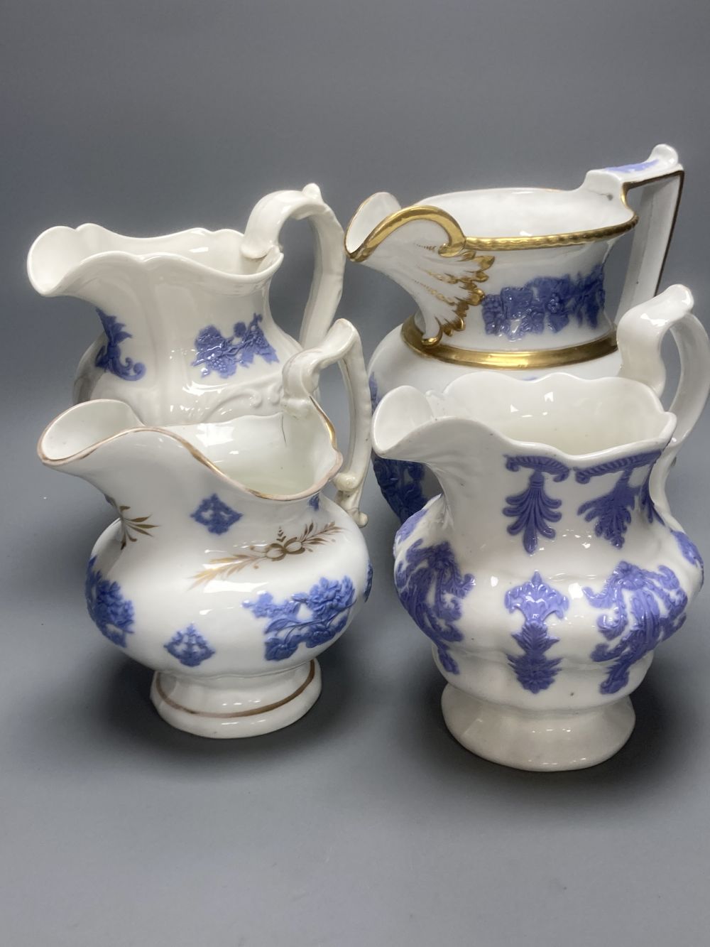 Four early 19th century Staffordshire jugs, each with lilac coloured floral applied panels, one dated 1826, tallest 22cm